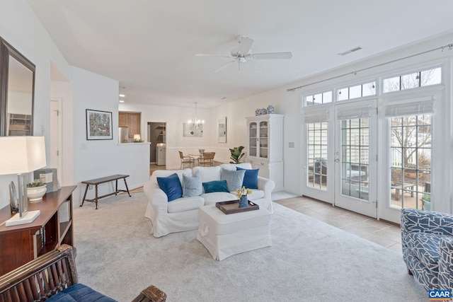 carpeted living room with french doors, visible vents, tile patterned flooring, and ceiling fan with notable chandelier