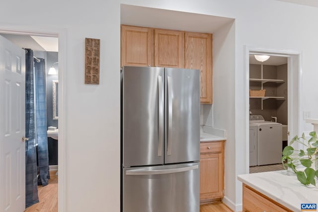 kitchen featuring freestanding refrigerator, light brown cabinets, separate washer and dryer, and light wood-type flooring