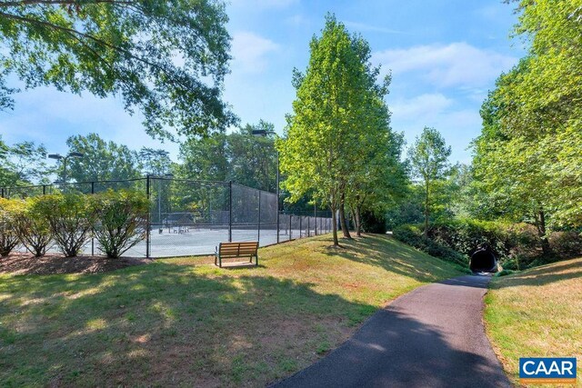 view of home's community featuring a yard, a tennis court, and fence