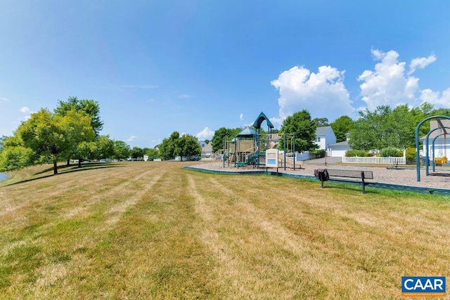 view of community featuring fence, playground community, and a lawn