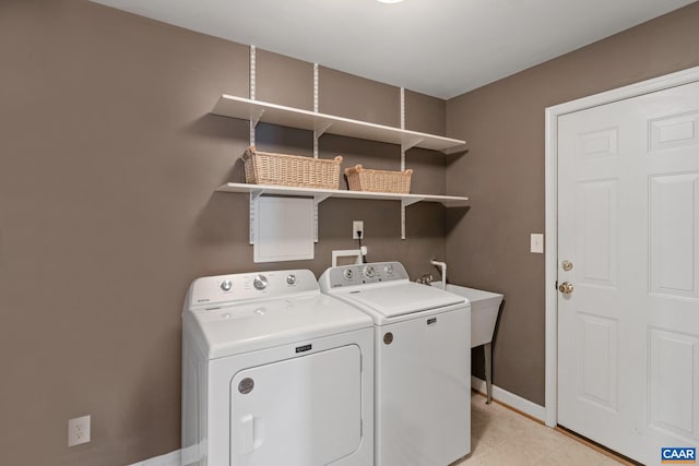 laundry area with laundry area, washer and clothes dryer, baseboards, and light tile patterned floors