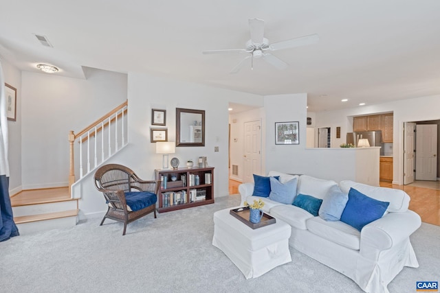 living area featuring stairway, ceiling fan, light carpet, and visible vents