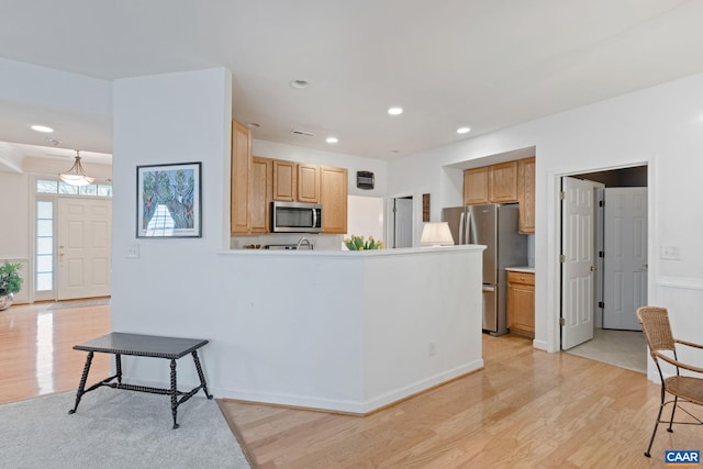 kitchen featuring a peninsula, stainless steel appliances, recessed lighting, light wood finished floors, and light brown cabinetry
