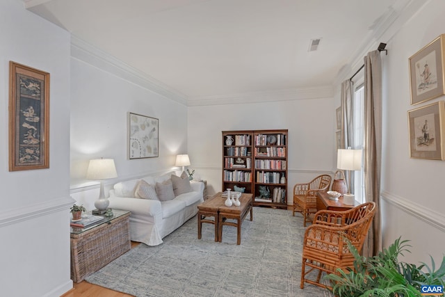 living room with crown molding, light wood-type flooring, visible vents, and a healthy amount of sunlight