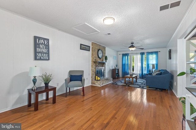  - living room featuring wood finished floors, a textured ceiling, a large fireplace, ceiling fan, and baseboards