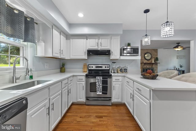  - kitchen with stainless steel appliances, under cabinet range hood, a sink, white cabinetry, and light countertops