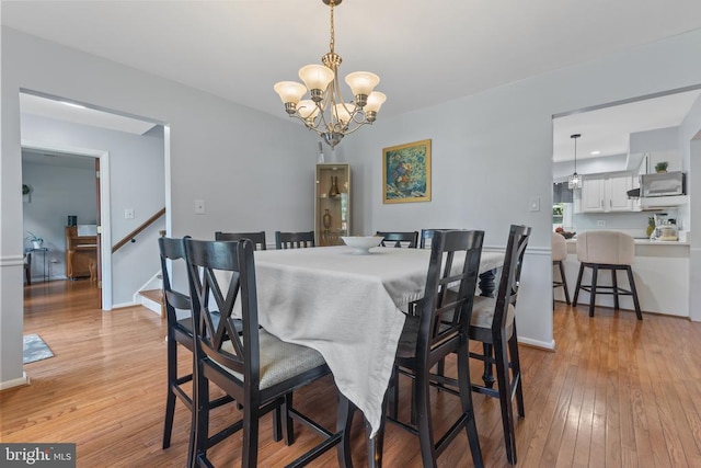  - dining room with light wood-style floors, a chandelier, and stairway