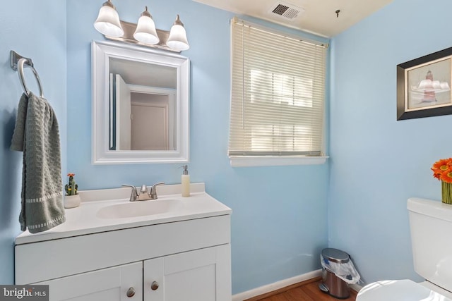  - bathroom featuring vanity, toilet, wood finished floors, and baseboards