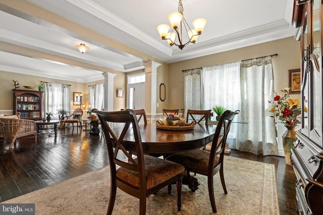  - dining area featuring ornate columns, a raised ceiling, healthy amount of natural light, dark wood finished floors, and crown molding