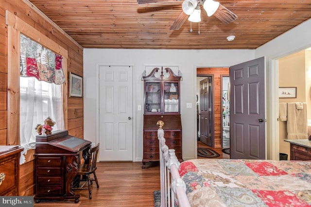 bedroom featuring wooden walls, hardwood / wood-style flooring, ceiling fan, and wooden ceiling