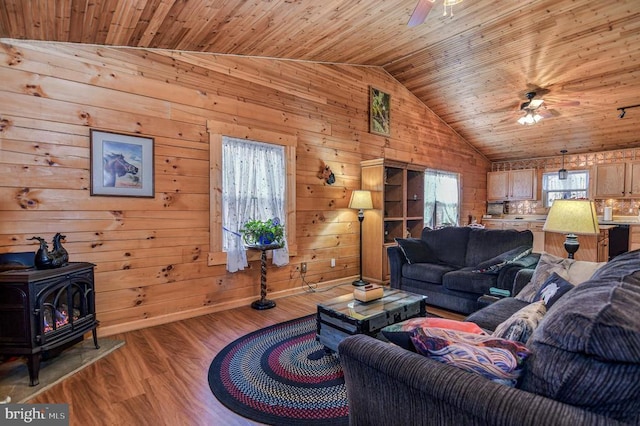 living room with light hardwood / wood-style floors, a wood stove, wooden ceiling, and ceiling fan