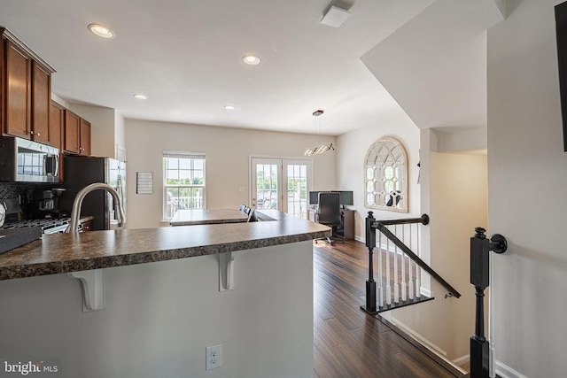 2015 Elm Tree Ct, Charlottesville, VA 22911 - kitchen with appliances with stainless steel finishes, a kitchen bar, dark countertops, a peninsula, and brown cabinetry