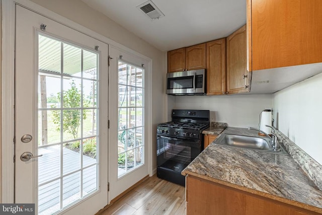 2015 Elm Tree Ct, Charlottesville, VA 22911 - kitchen featuring black gas range, stainless steel microwave, light wood finished floors, and brown cabinets