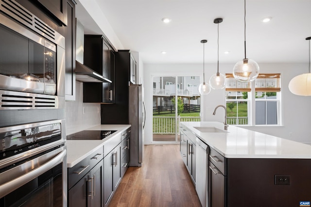 4454 Alston St, Crozet, VA 22932 - kitchen with appliances with stainless steel finishes, light countertops, wall chimney exhaust hood, a center island with sink, and wood finished floors