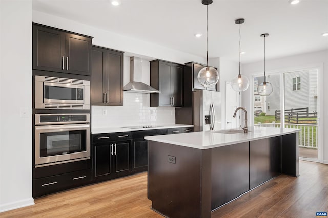 4454 Alston St, Crozet, VA 22932 - kitchen featuring appliances with stainless steel finishes, wall chimney exhaust hood, light wood-style flooring, tasteful backsplash, and light countertops