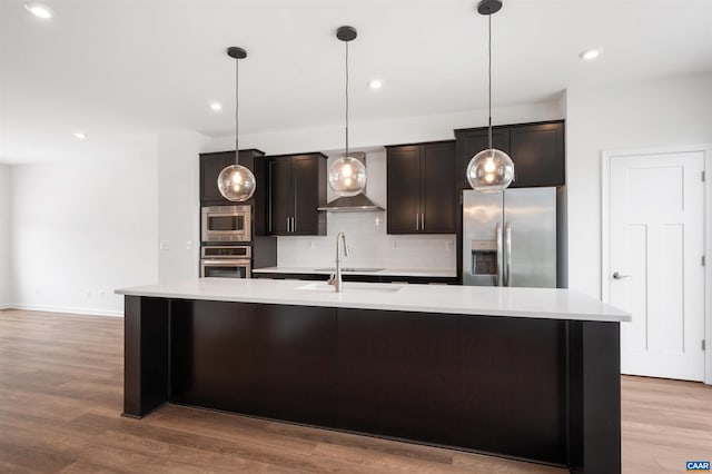 4454 Alston St, Crozet, VA 22932 - kitchen with stainless steel appliances, light countertops, decorative backsplash, a center island with sink, and wall chimney range hood