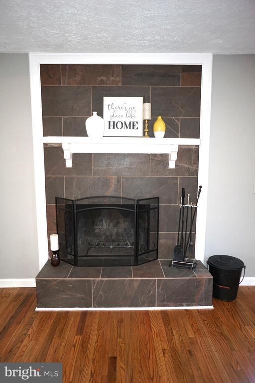 7435 Courthouse Rd, Spotsylvania, VA 22551 - detailed view of a tiled fireplace, wood finished floors, baseboards, and a textured ceiling