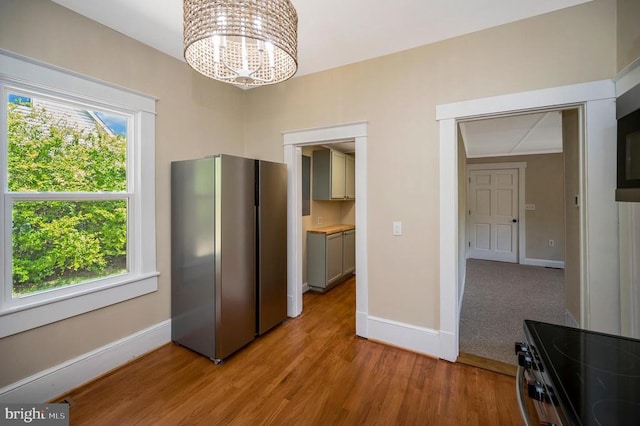 unfurnished dining area featuring an inviting chandelier, baseboards, and light wood-style flooring