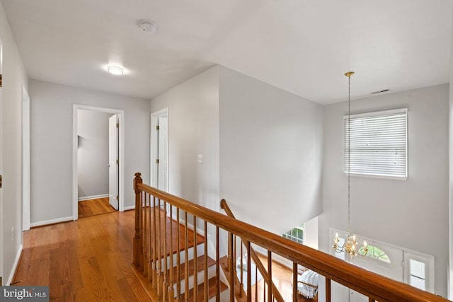  - hall featuring an upstairs landing, wood finished floors, baseboards, and a chandelier