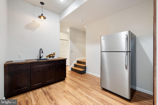  - kitchen with freestanding refrigerator, light wood-style flooring, a sink, baseboards, and dark brown cabinetry