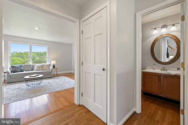  - hall featuring light wood-type flooring, baseboards, and a sink