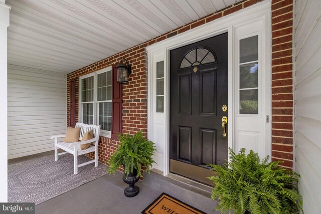  - doorway to property with a porch and brick siding