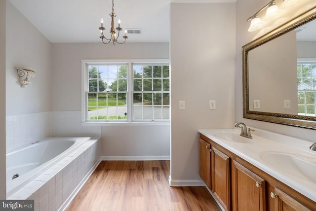  - full bath featuring a chandelier, a bath, double vanity, wood finished floors, and baseboards