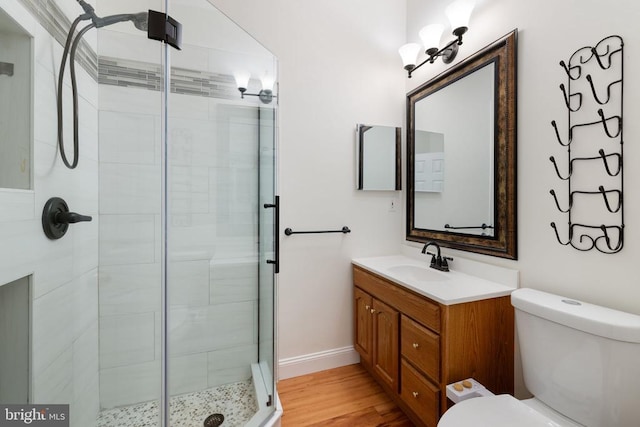  - bathroom featuring toilet, a stall shower, vanity, wood finished floors, and baseboards