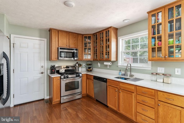 5008 Blake Dr, Fredericksburg, VA 22407 - kitchen with appliances with stainless steel finishes, dark wood-type flooring, brown cabinets, light countertops, and glass insert cabinets