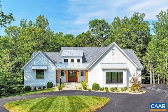 modern farmhouse with french doors, metal roof, aphalt driveway, a front lawn, and a standing seam roof