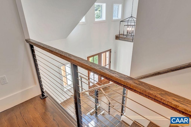 stairs featuring an inviting chandelier, a towering ceiling, and wood finished floors