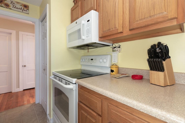 310 Spotswood Ave E, Elkton, VA 22827 - kitchen with white appliances, light countertops, brown cabinetry, and light tile patterned flooring