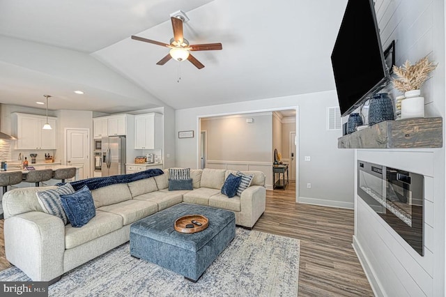 5220 Wyndemere Cir, Mineral, VA 23117 - living area featuring a glass covered fireplace, wood finished floors, ceiling fan, vaulted ceiling, and baseboards