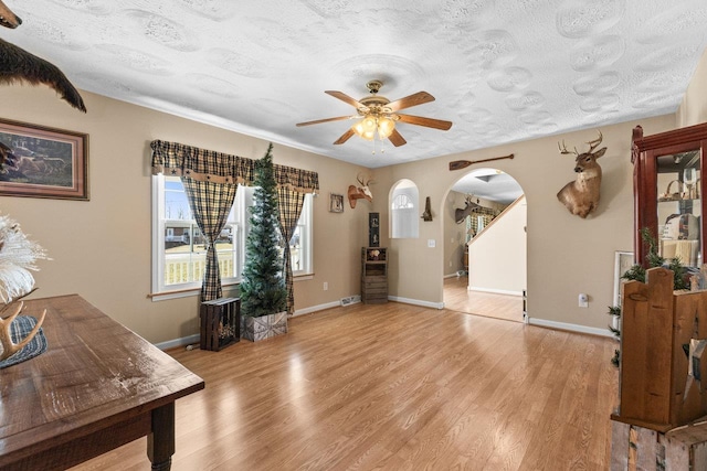 18785 Red Brush Rd, Elkton, VA 22827 - interior space with a ceiling fan, light wood-style flooring, a textured ceiling, baseboards, and arched walkways