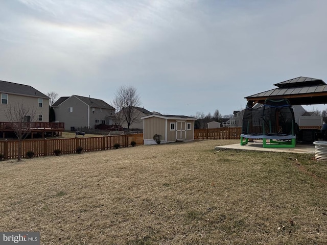 view of yard with a trampoline, a gazebo, an outdoor structure, a storage shed, and a residential view