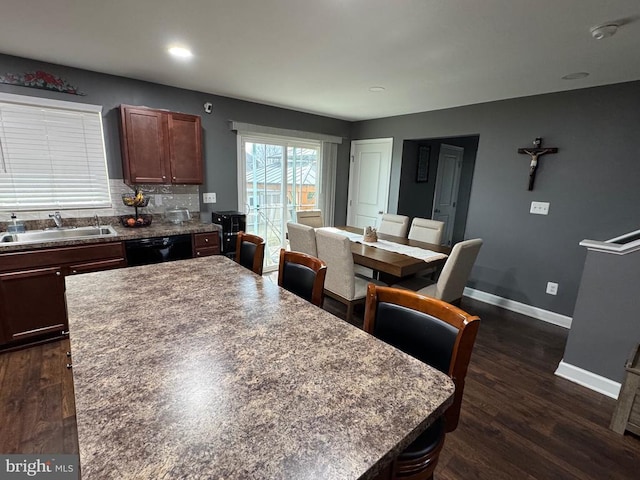 kitchen with black dishwasher, a sink, baseboards, and dark wood-style floors