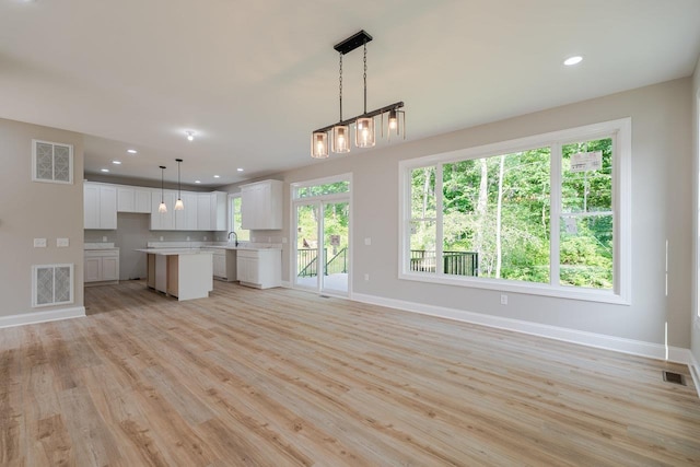 4125 Romney Ct, Rockingham, VA 22802 - kitchen with light countertops, open floor plan, white cabinetry, light wood-style flooring, and a center island