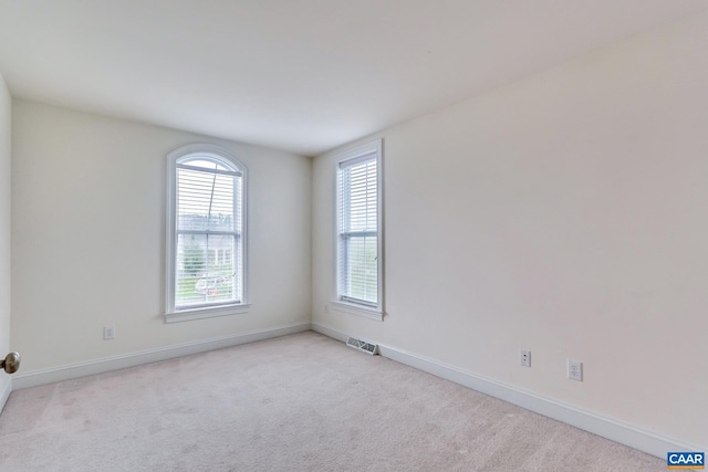spare room with baseboards, visible vents, and light colored carpet