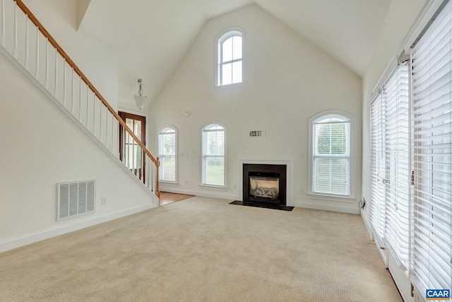 unfurnished living room featuring stairway, visible vents, carpet floors, and a fireplace with flush hearth