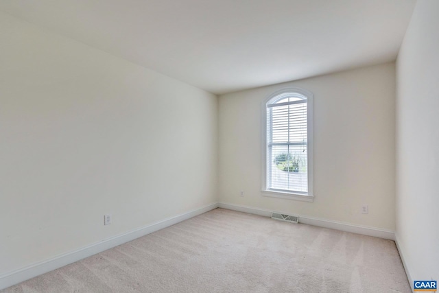 spare room with light colored carpet, baseboards, and visible vents