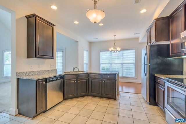 kitchen featuring a sink, a peninsula, stainless steel appliances, dark brown cabinetry, and an inviting chandelier