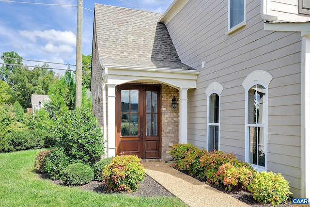 doorway to property featuring a shingled roof and stone siding