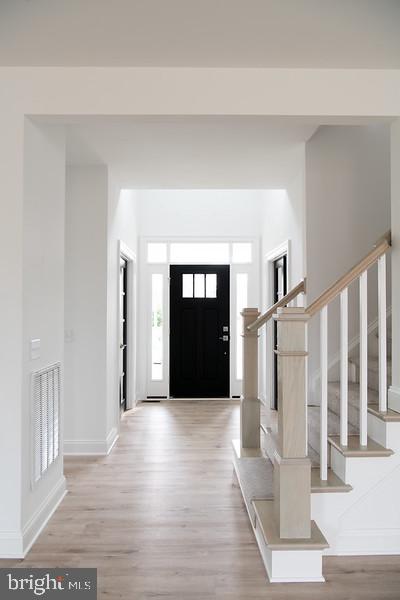 entrance foyer featuring stairs, baseboards, visible vents, and light wood-style floors