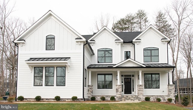 view of front of house featuring a porch, a front lawn, a standing seam roof, and board and batten siding