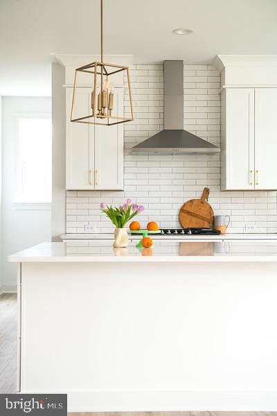kitchen with white cabinetry, decorative backsplash, light countertops, and wall chimney exhaust hood
