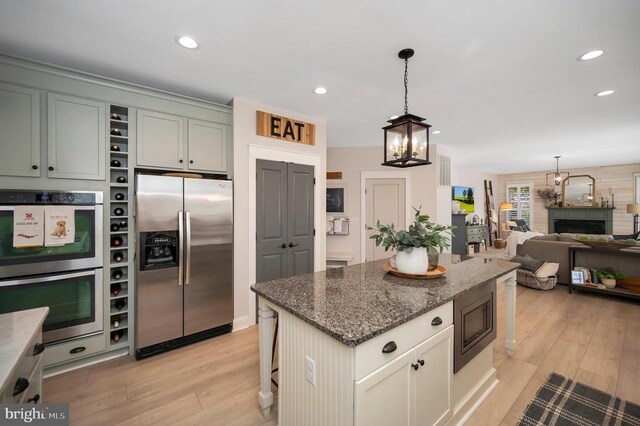 11001 Waterstone Pl, Spotsylvania, VA 22551 - kitchen with stainless steel appliances, a chandelier, light wood finished floors, dark stone counters, and hanging light fixtures