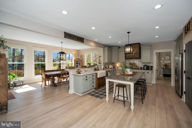 11001 Waterstone Pl, Spotsylvania, VA 22551 - kitchen featuring gray cabinetry, a peninsula, freestanding refrigerator, a sink, and a kitchen bar