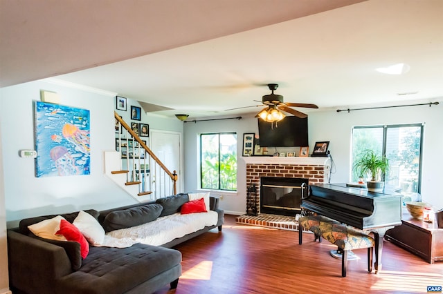 living room with plenty of natural light, stairway, wood finished floors, and ceiling fan