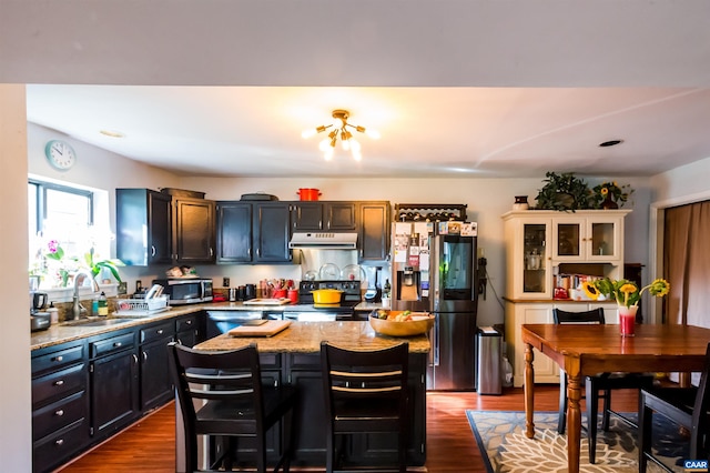 kitchen with dark wood-type flooring, stainless steel appliances, range hood, and a sink