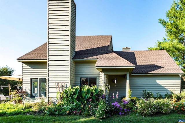 view of front facade featuring a chimney and roof with shingles